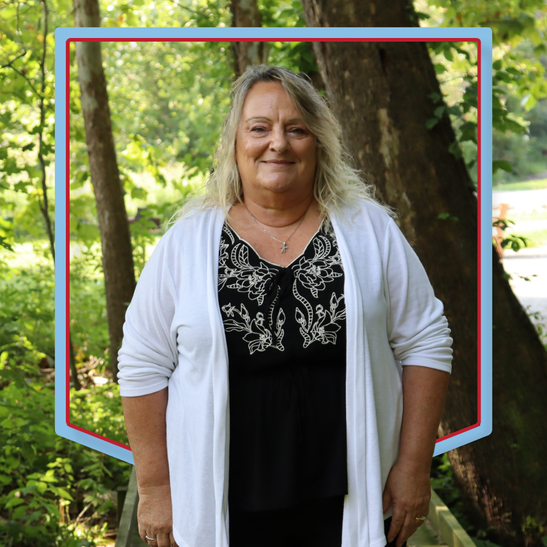 Lisa Raber poses for a photo with a wooded background.